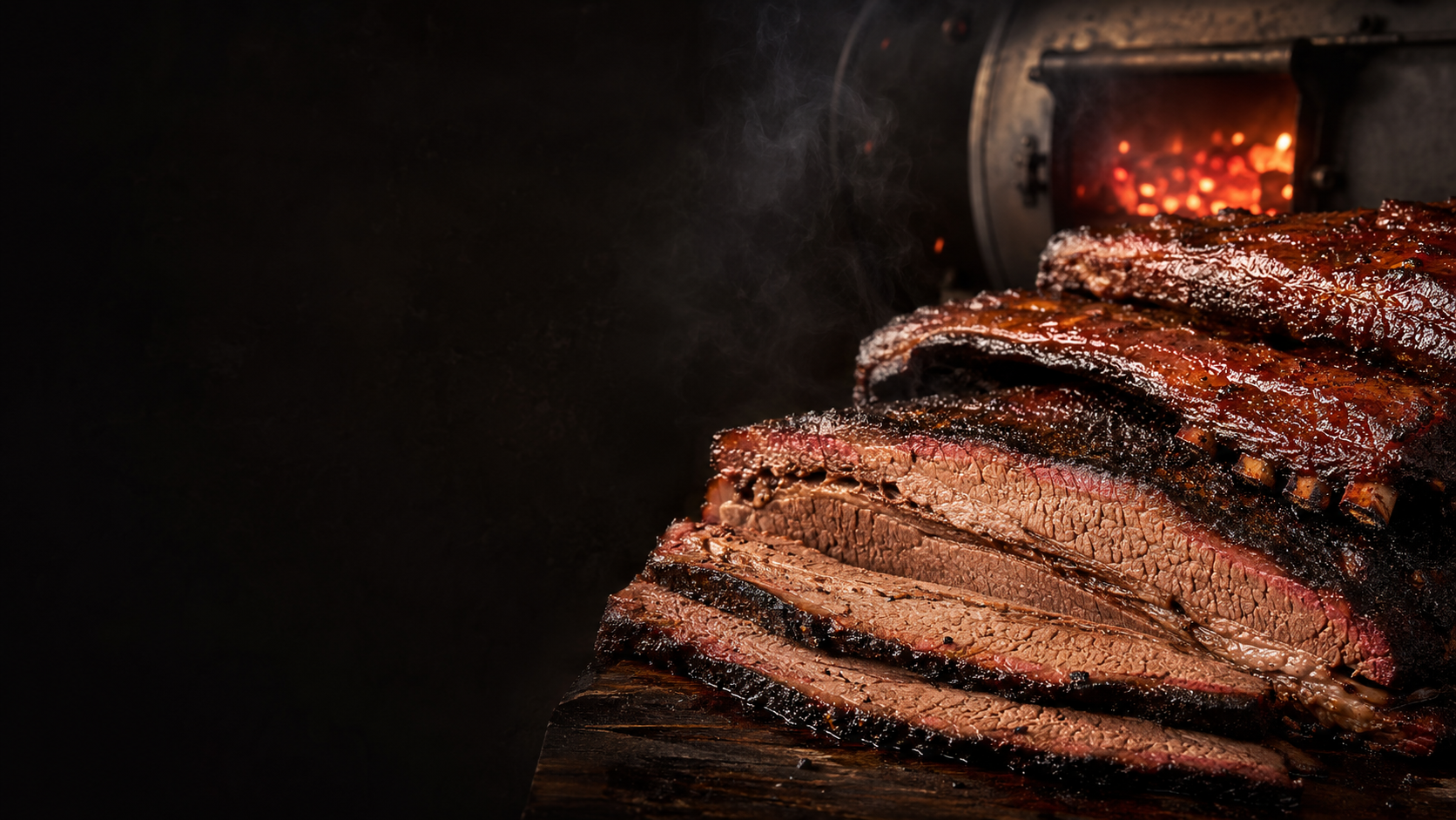 Brisket and ribs beside a glowing smoker