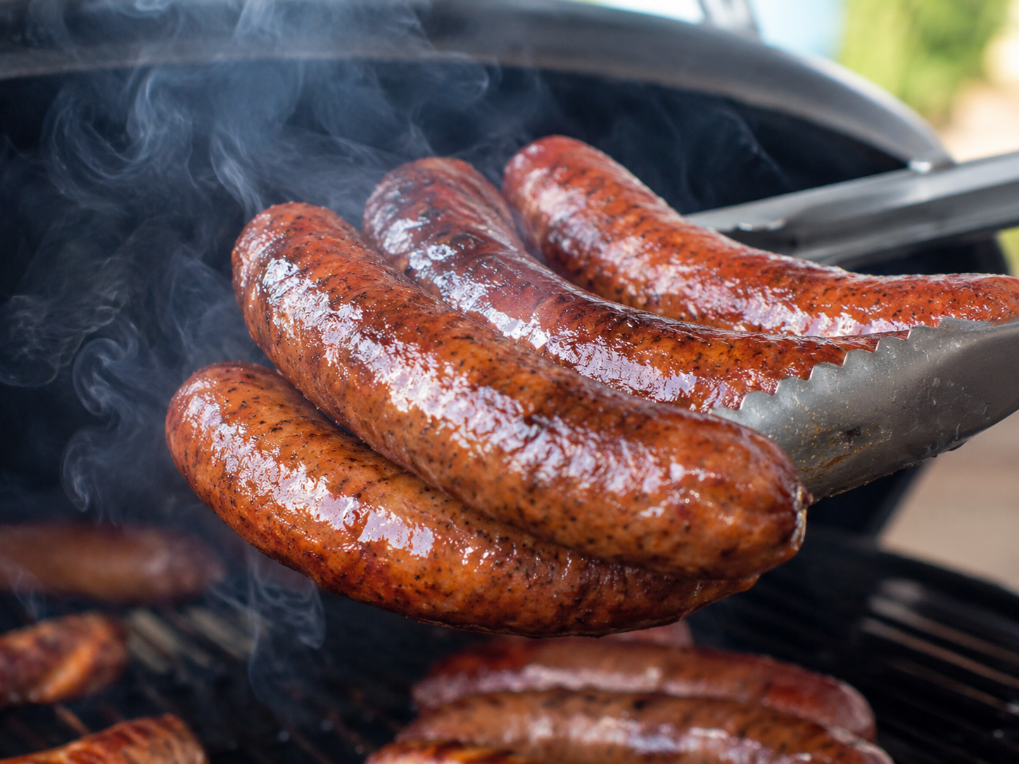 Smoked sausage lifted from a grill